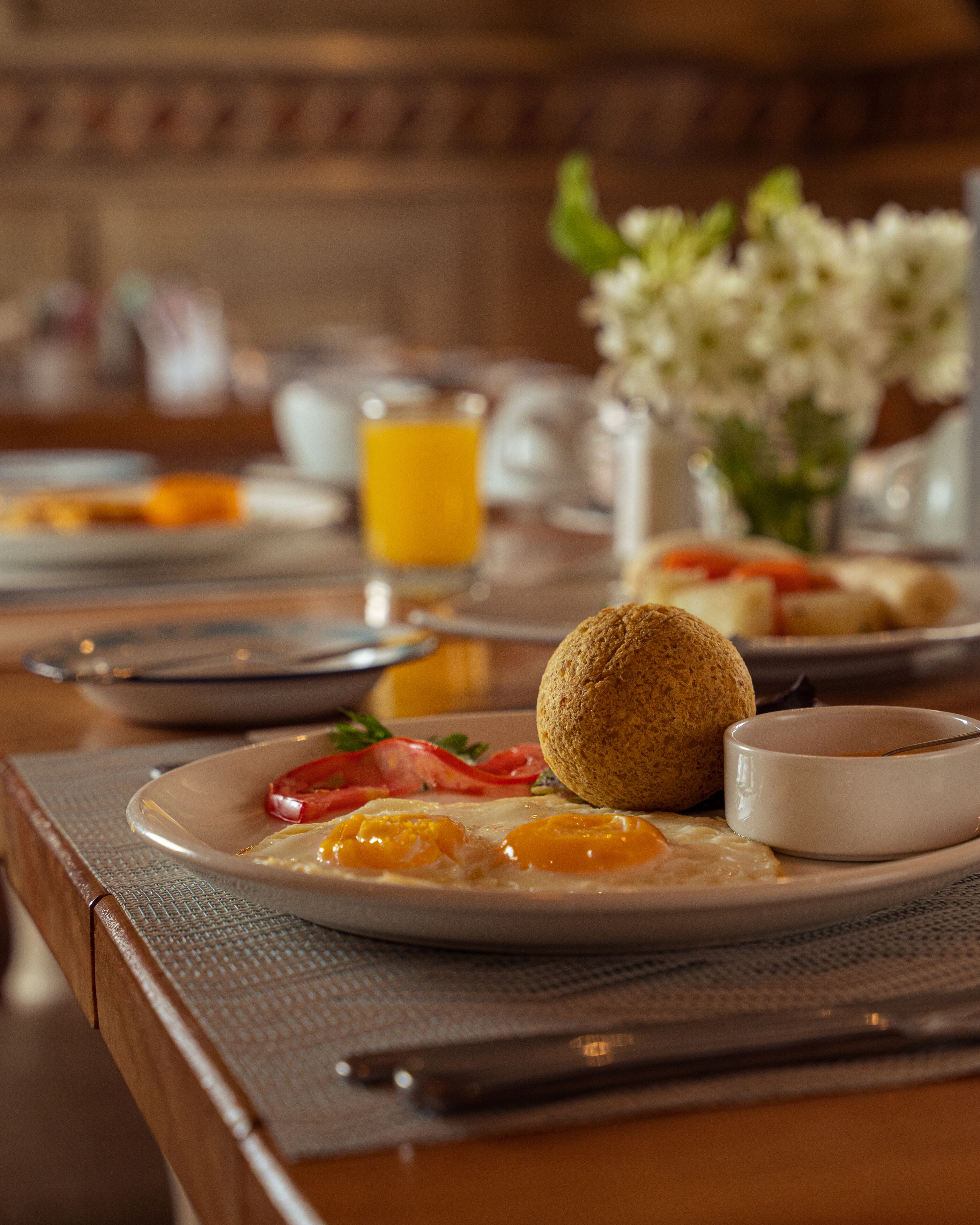 Un desayuno con huevos, un muffin y un vaso de jugo de naranja sobre una mesa.