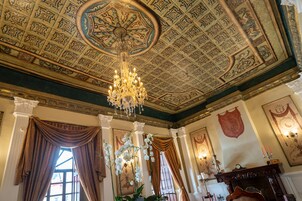 A grand room with ornate ceiling, chandeliers, and classical decor.