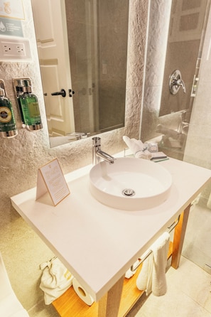 A bathroom with a white sink, a mirror, and toiletries on the wall. - Hotel Boutique Santa Lucia (Cuenca)