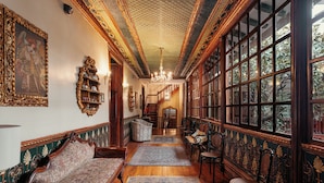 Un vaste hall d’entrée agrémenté de meubles en bois richement décorés, une grande fenêtre donnant sur un paysage verdoyant et un lustre.