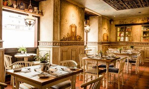A dining area with multiple tables and chairs, a large clock on the wall, and a variety of decorative items on shelves. - Hotel Boutique Santa Lucia (Cuenca)