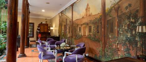 A room with a mural, a dining area with purple chairs, and a wooden cabinet.