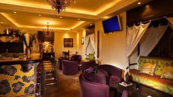 Un área de descanso bien iluminada con bar, asientos y televisor.