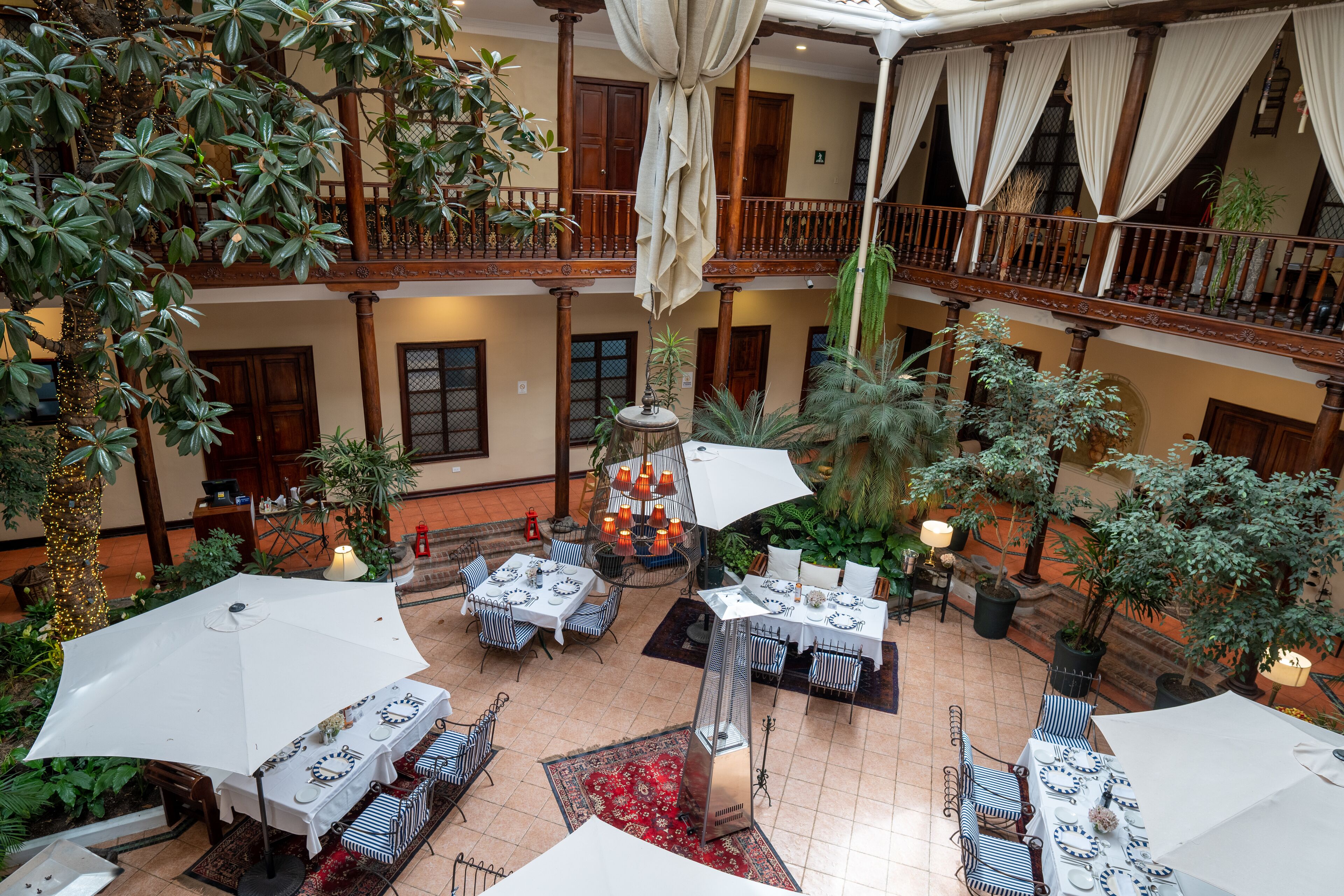 An indoor courtyard with multiple dining areas, potted plants, and a central fountain.