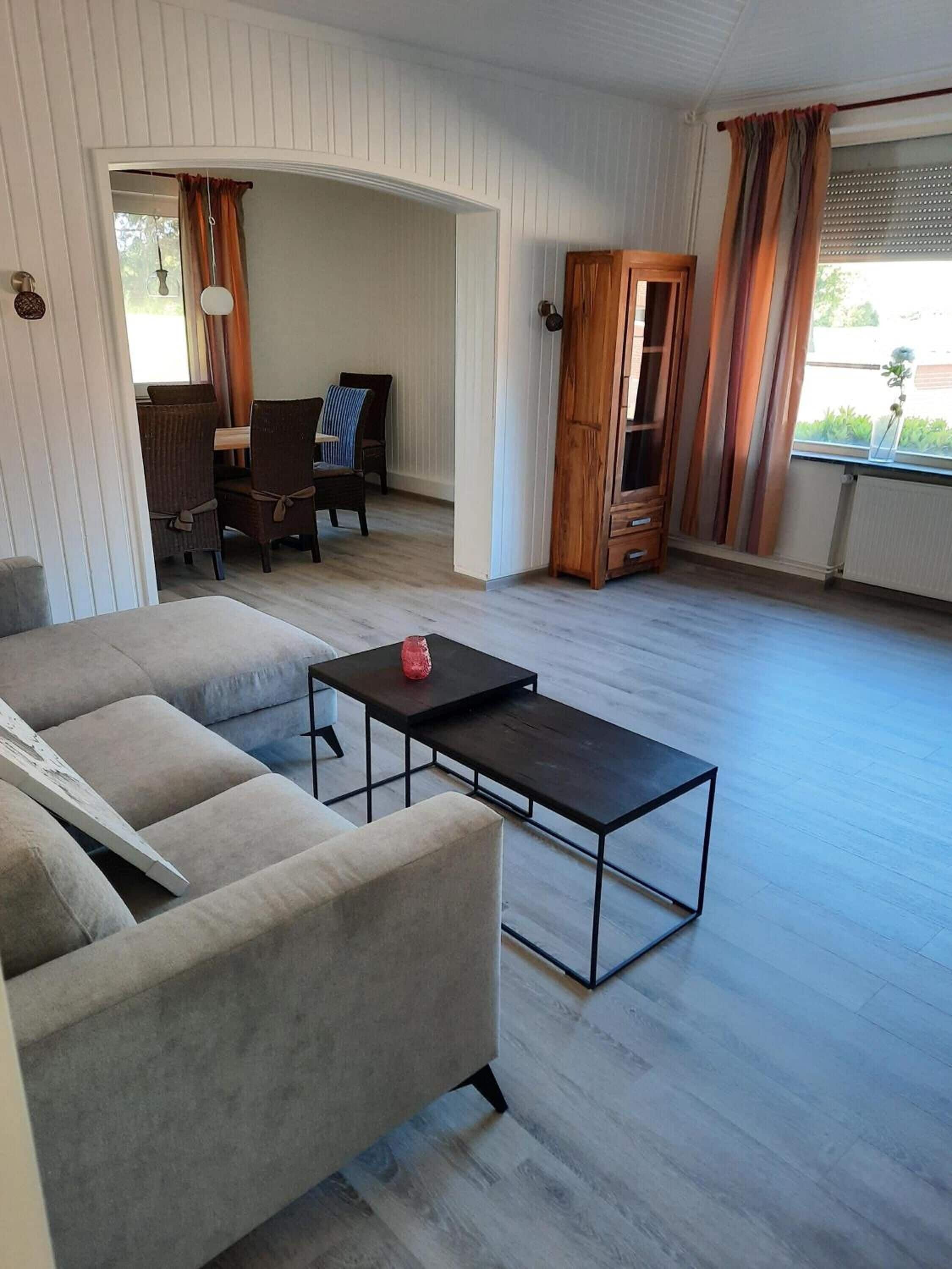 A living room with a sofa, a coffee table, and a dining area with chairs and a table.