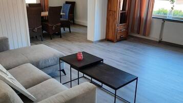 A living room with a sofa, a coffee table, and a dining area with chairs and a table.