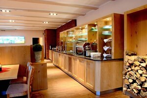Un restaurante con una barra larga, armarios de madera y una exhibición de alimentos.