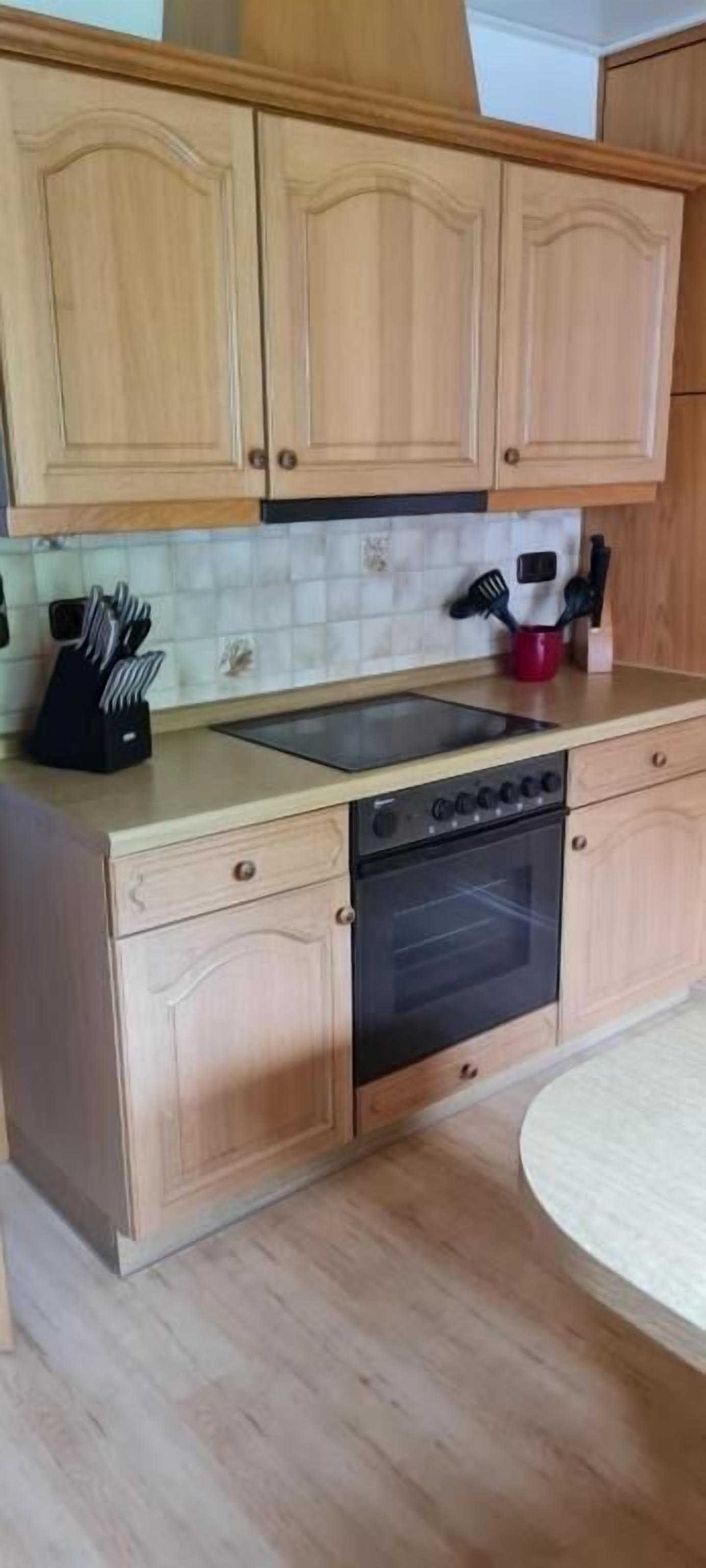 A kitchen with wooden cabinets, a black stove, and a red mug on the countertop.