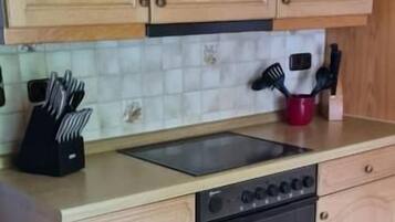 A kitchen with wooden cabinets, a black stove, and a red mug on the countertop.