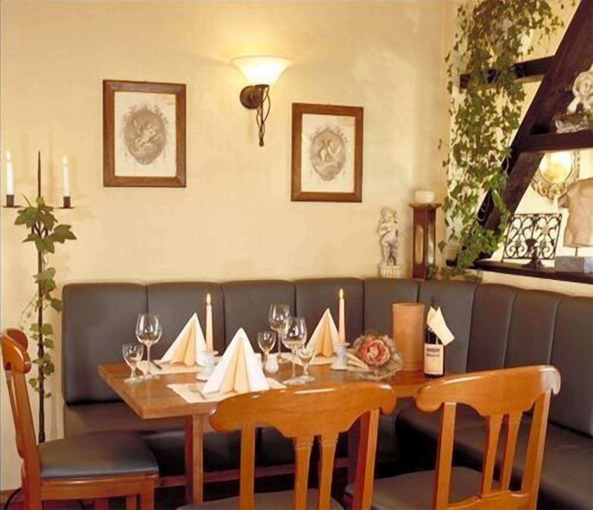 Un comedor con una mesa de madera dispuesta para cuatro, un banco acolchado y cuadros en la pared.