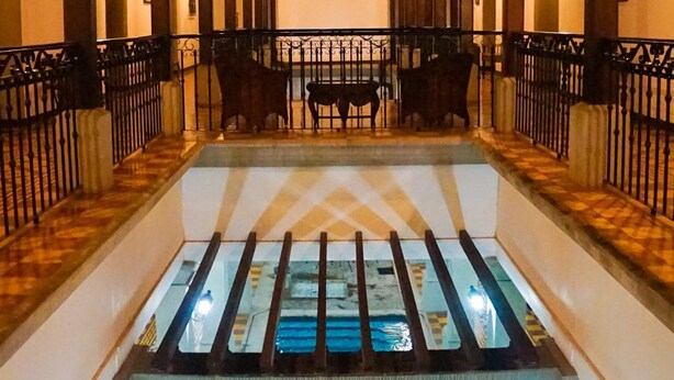 Uma área de piscina com barreira de vidro, guarda-corpos de madeira e assentos.