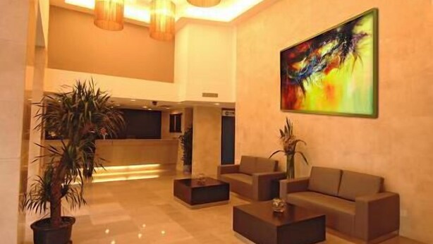 Een ruime lobby met een receptiebalie, een zithoek en een groot abstract schilderij aan de muur.