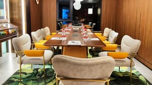 Een vergaderruimte met een lange tafel, meerdere stoelen en een moderne kroonluchter.