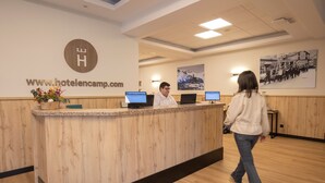 Un mostrador de recepción de hotel con una encimera de madera, dos monitores de computadora y una dirección web en la pared.