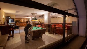 Mesa de billar en una sala con bar y zona de estar.