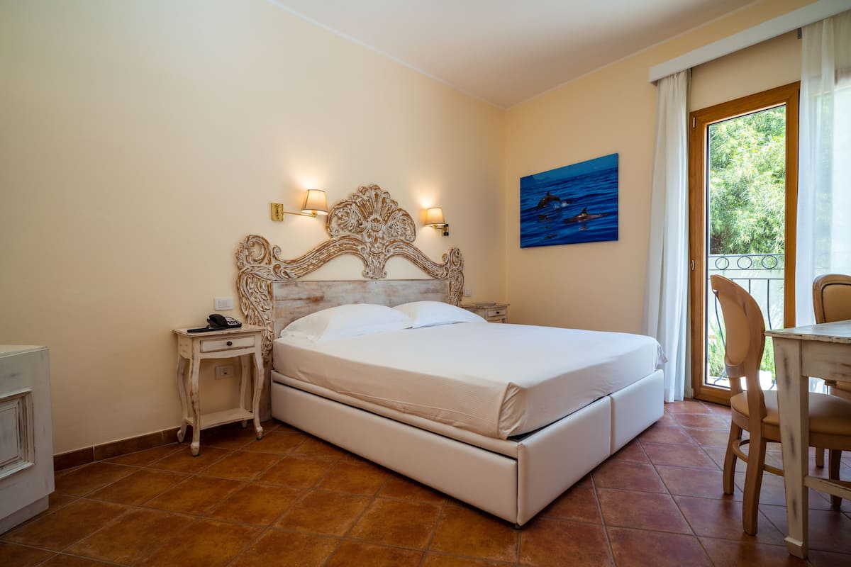 A bedroom with a large bed, a nightstand, a chair, and a painting on the wall.