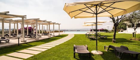 A patio area with outdoor seating, umbrellas, and a view of the sea.