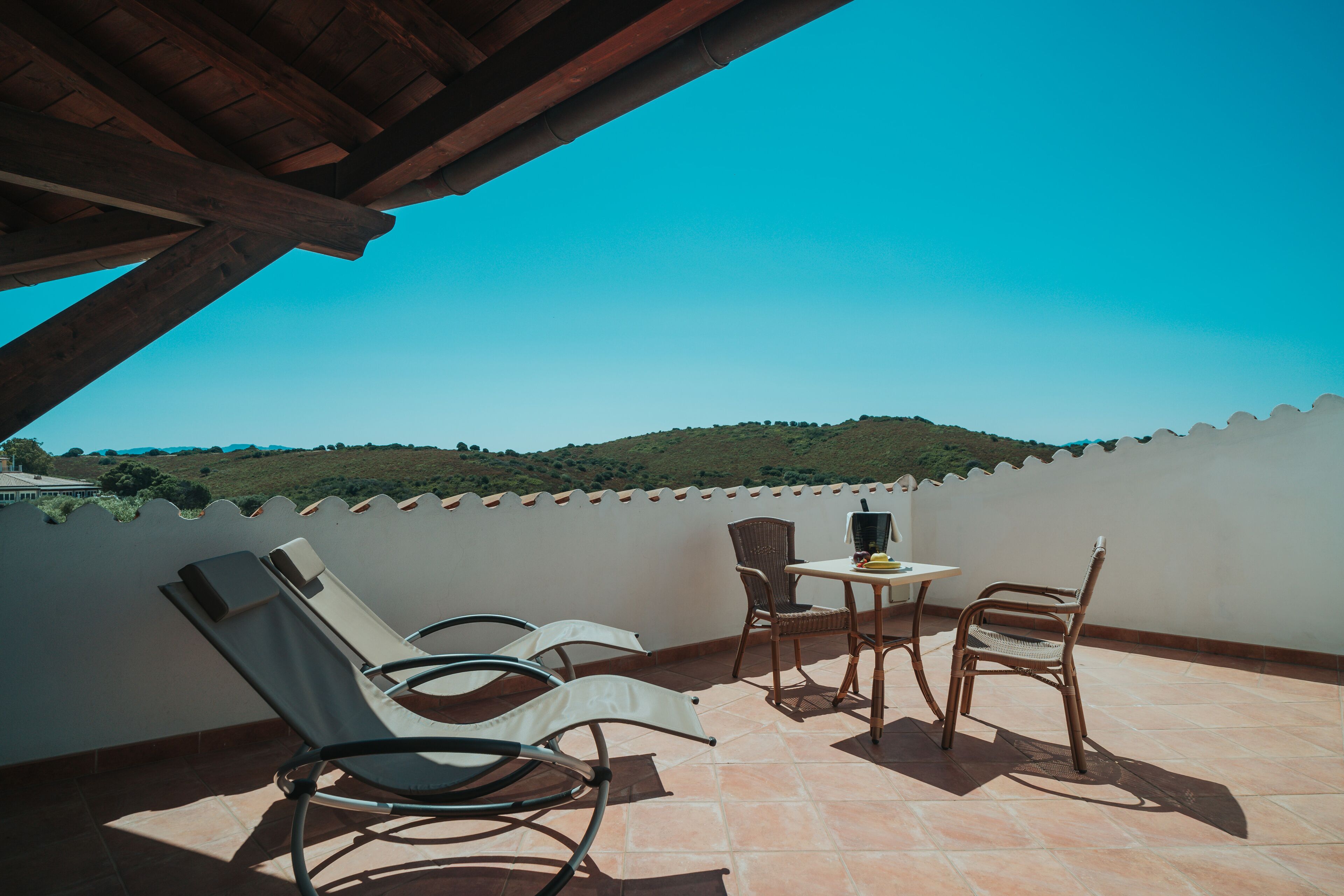 Una terraza con dos sillones de descanso y una mesa, con vistas a un paisaje montañoso.