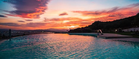 Una piscina al aire libre de temporada, sombrillas, tumbonas