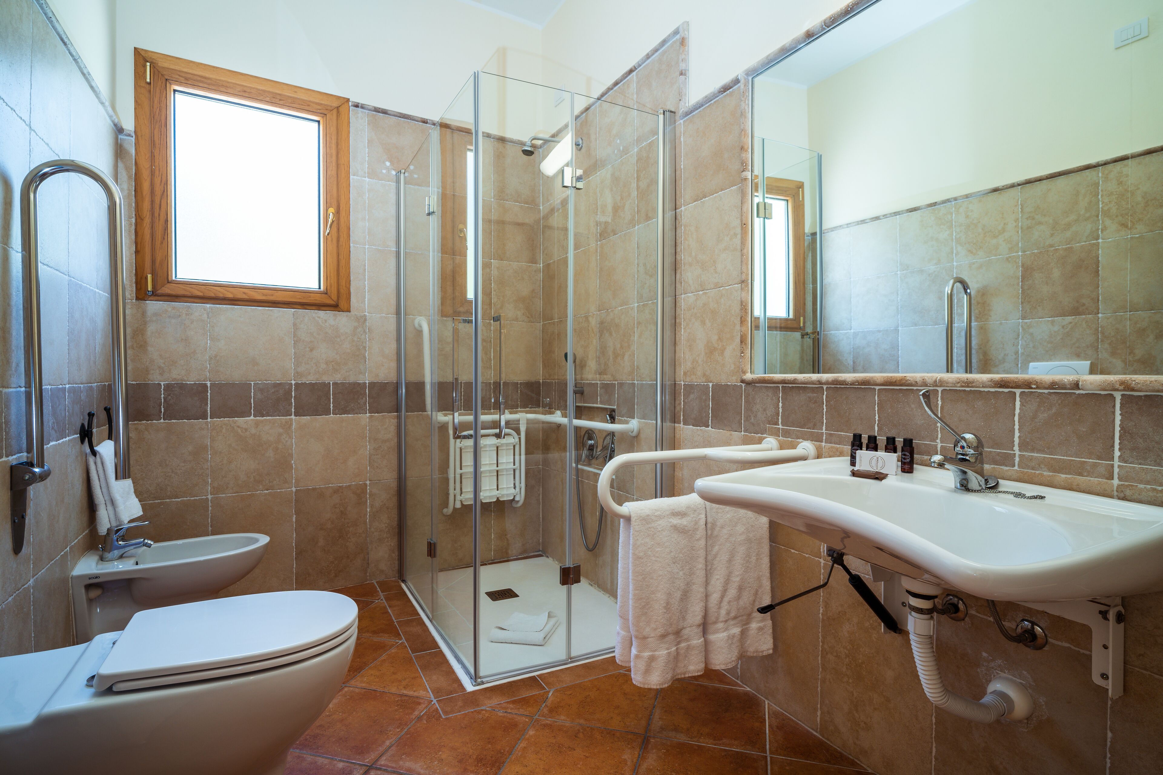 Un baño con ducha envuelta en vidrio, un inodoro y un lavabo con espejo.