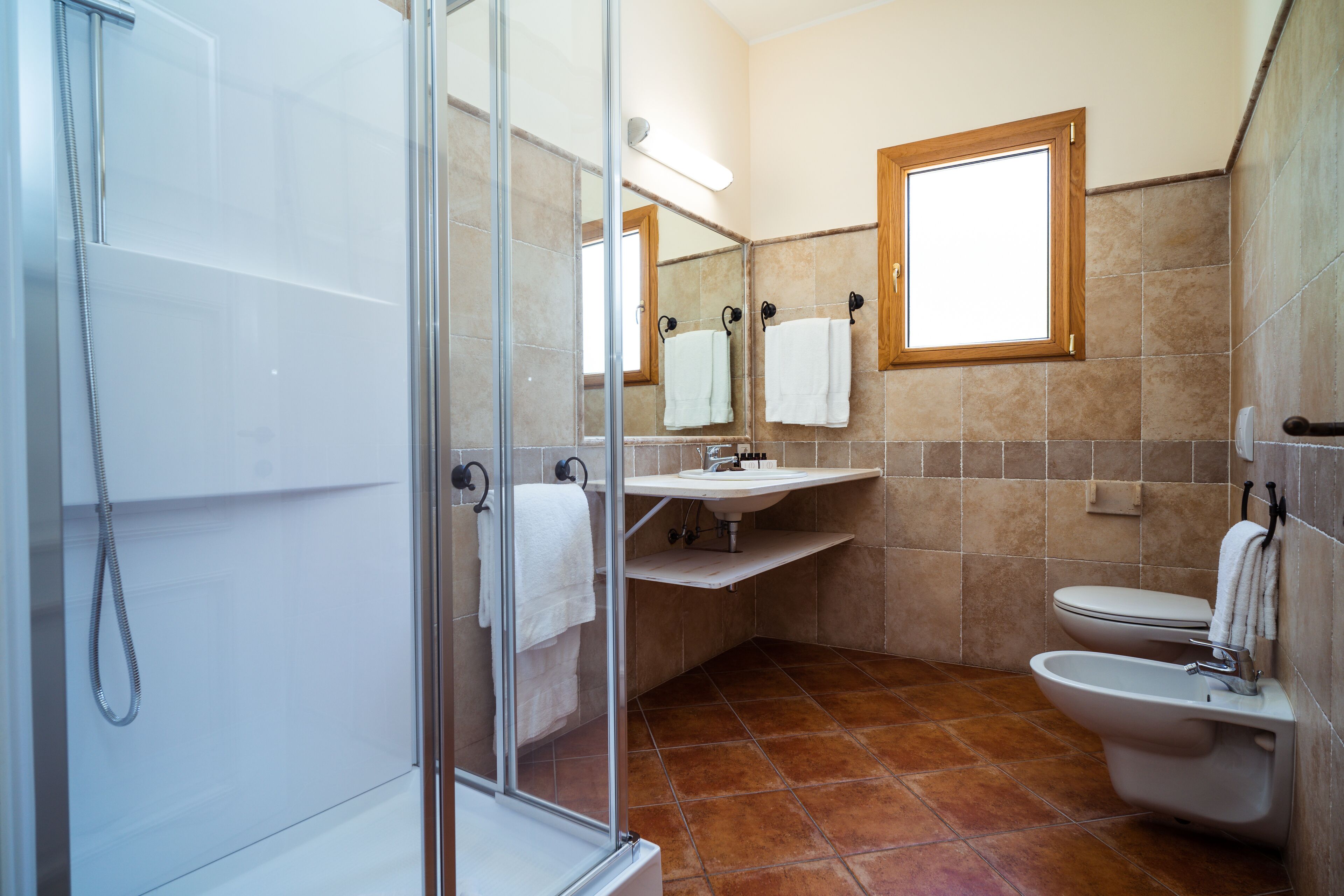 A modern bathroom with a glass shower enclosure, a sink, a toilet, and a bidet.