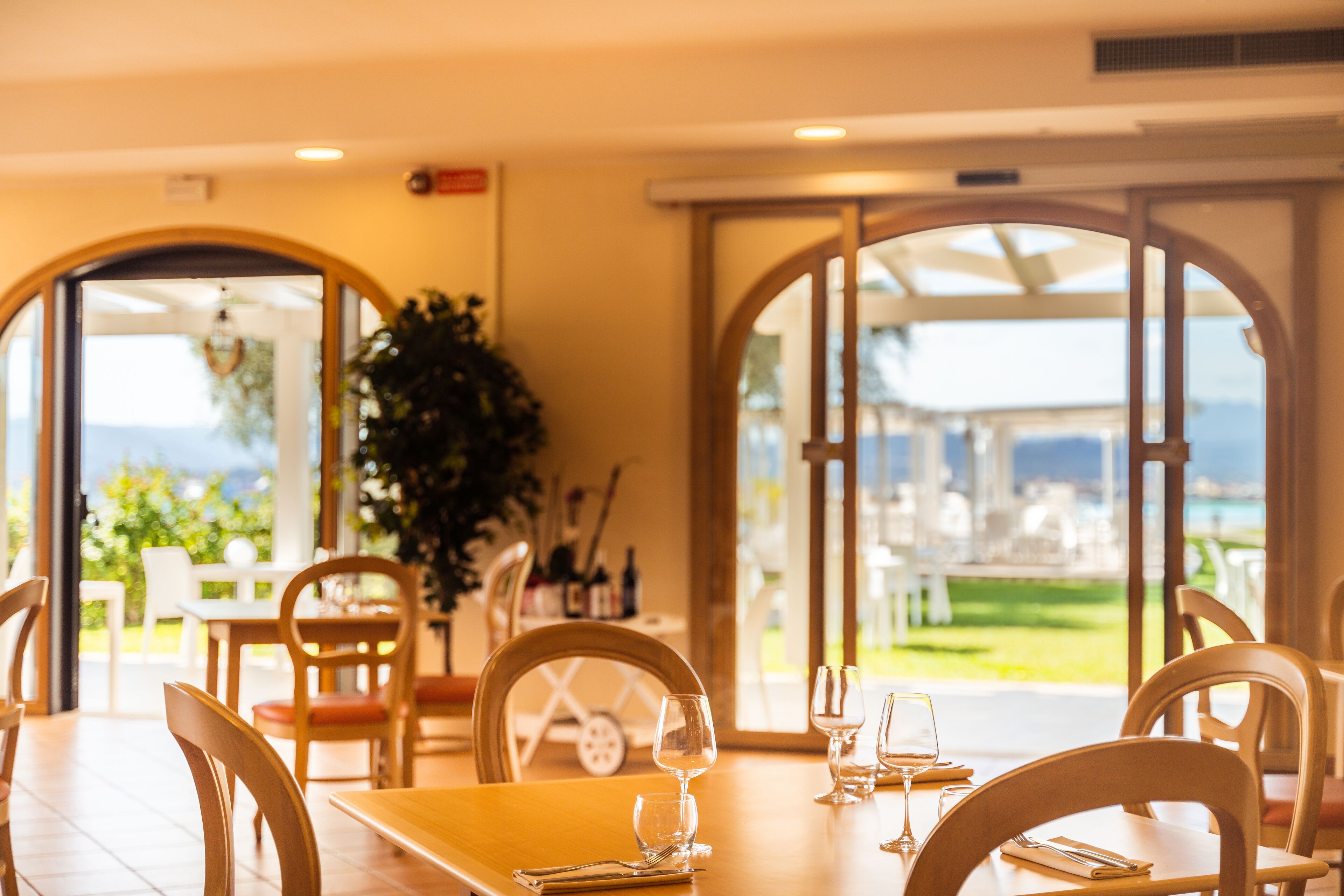 A dining area with tables and chairs, large windows, and a view of the outdoors.