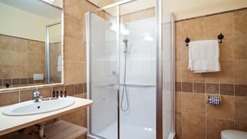 A bathroom with a glass-enclosed shower, a sink, and a toilet.
