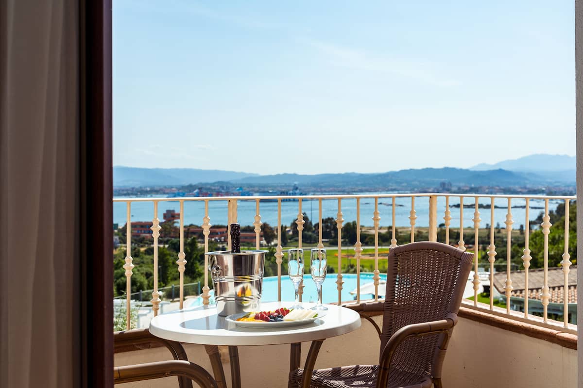 A balcony with a table, a chair, a bottle of champagne, and a plate of fruit.