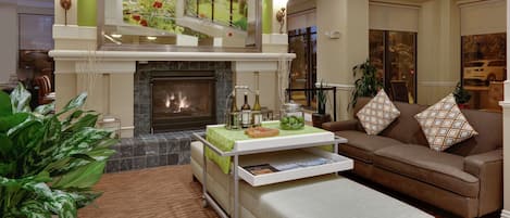 A living room with a fireplace, a sofa, a coffee table, and a large potted plant.
