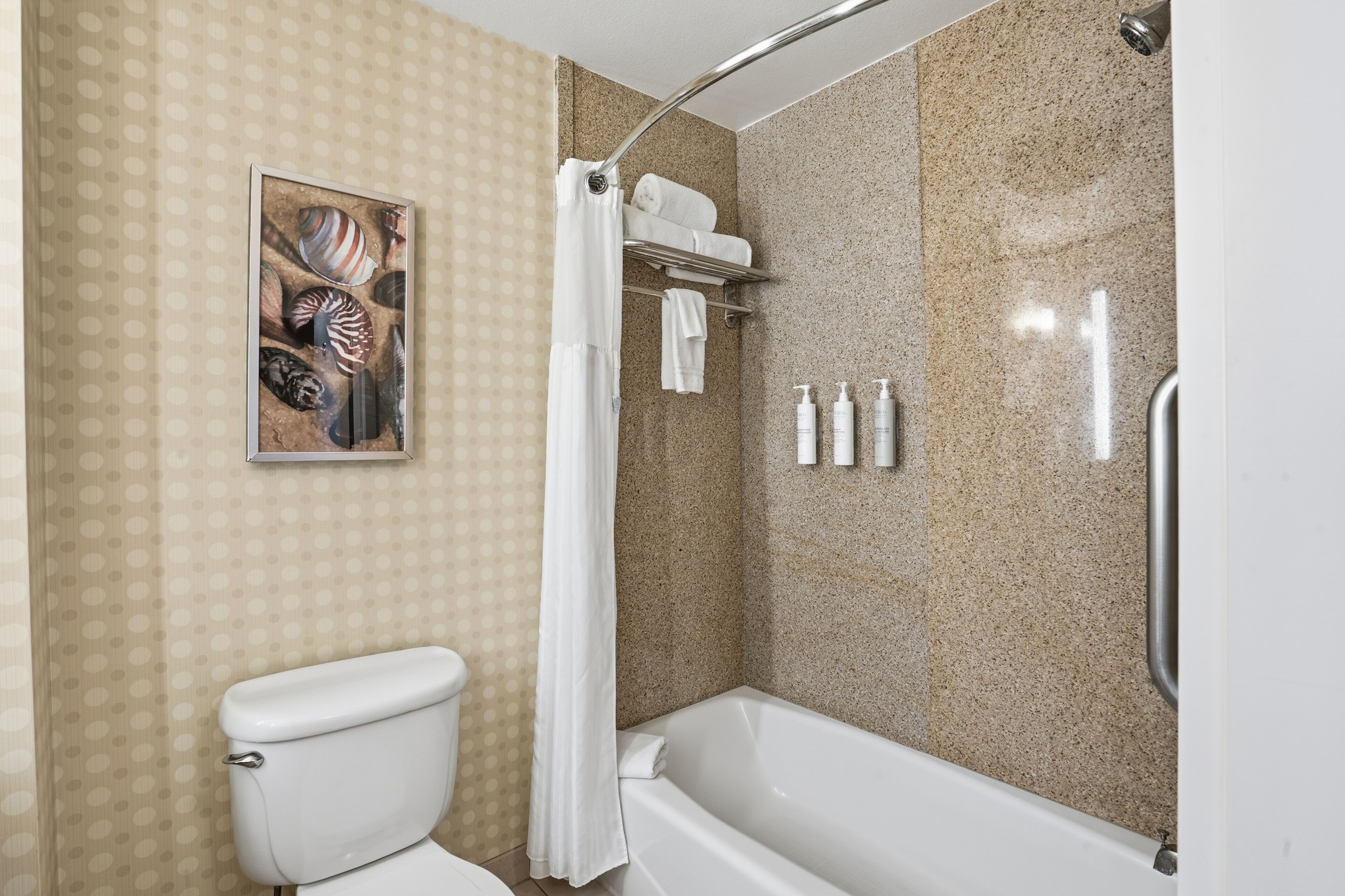 A bathroom with a toilet, bathtub, shower curtain, and a towel rack with towels.