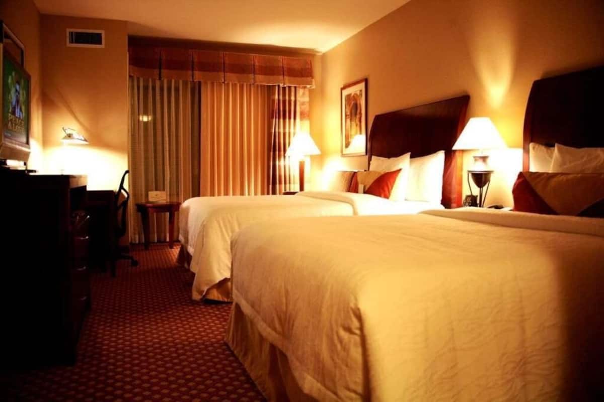 Een hotelkamer met twee bedden, een bureau, een stoel en een lamp.