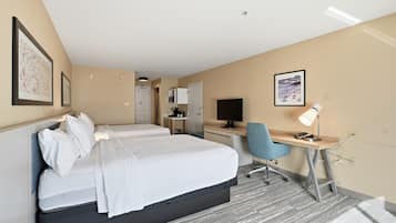A hotel room with a bed, desk, chair, and a television.