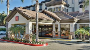 A hotel with a covered entrance, palm trees, and a clear sky.