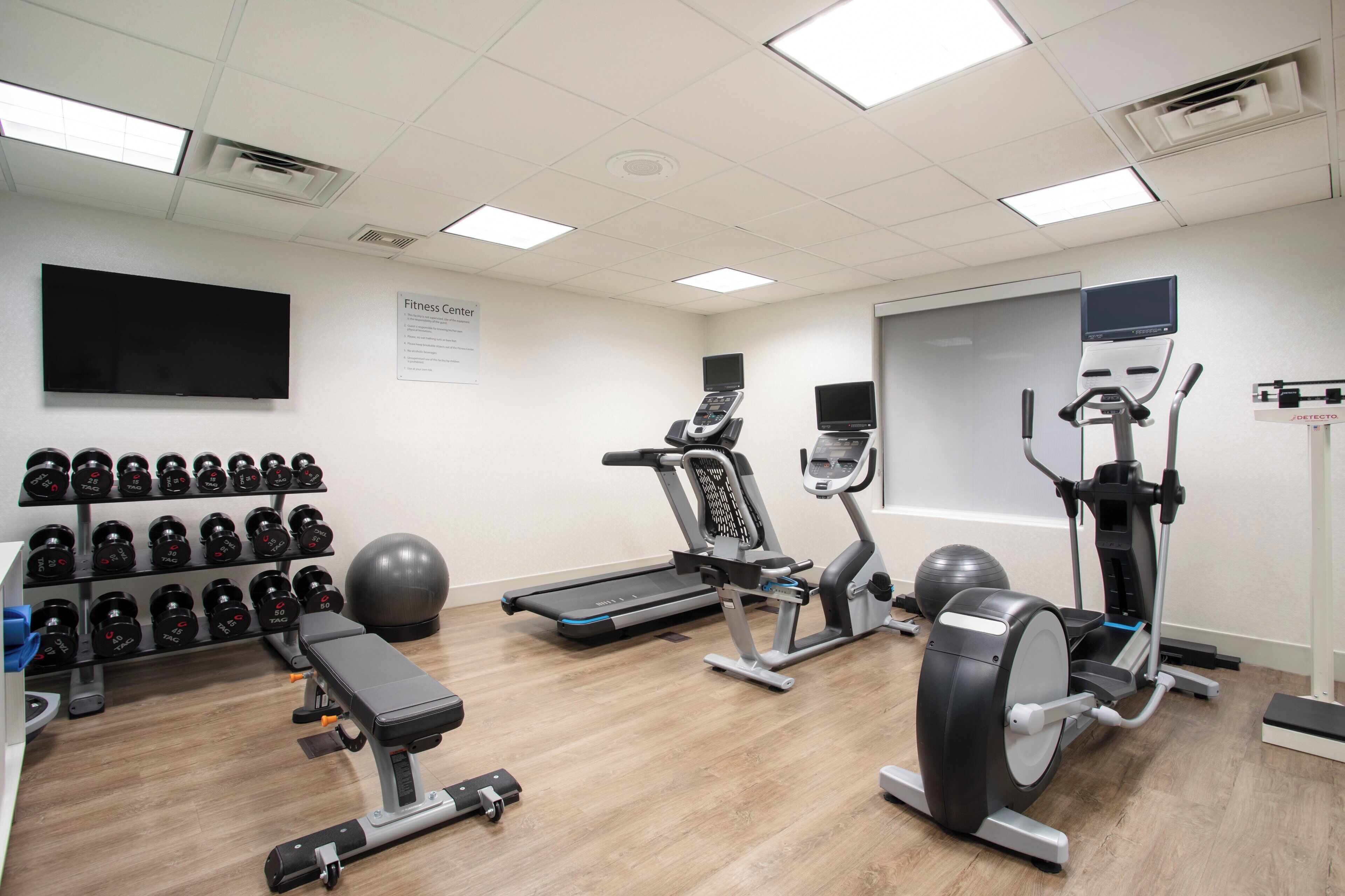 A fitness center with treadmills, elliptical machines, a bench, dumbbells, and a stationary bike.