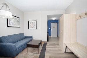 Un salon moderne avec un canapé bleu, une table basse et des œuvres d’art abstraites accrochées aux murs.