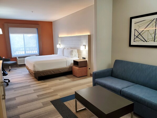 A hotel room with a bed, a desk, a chair, a sofa, and a painting on the wall. - Holiday Inn Express & Suites Phoenix - Glendale Sports Dist by IHG (Glendale)