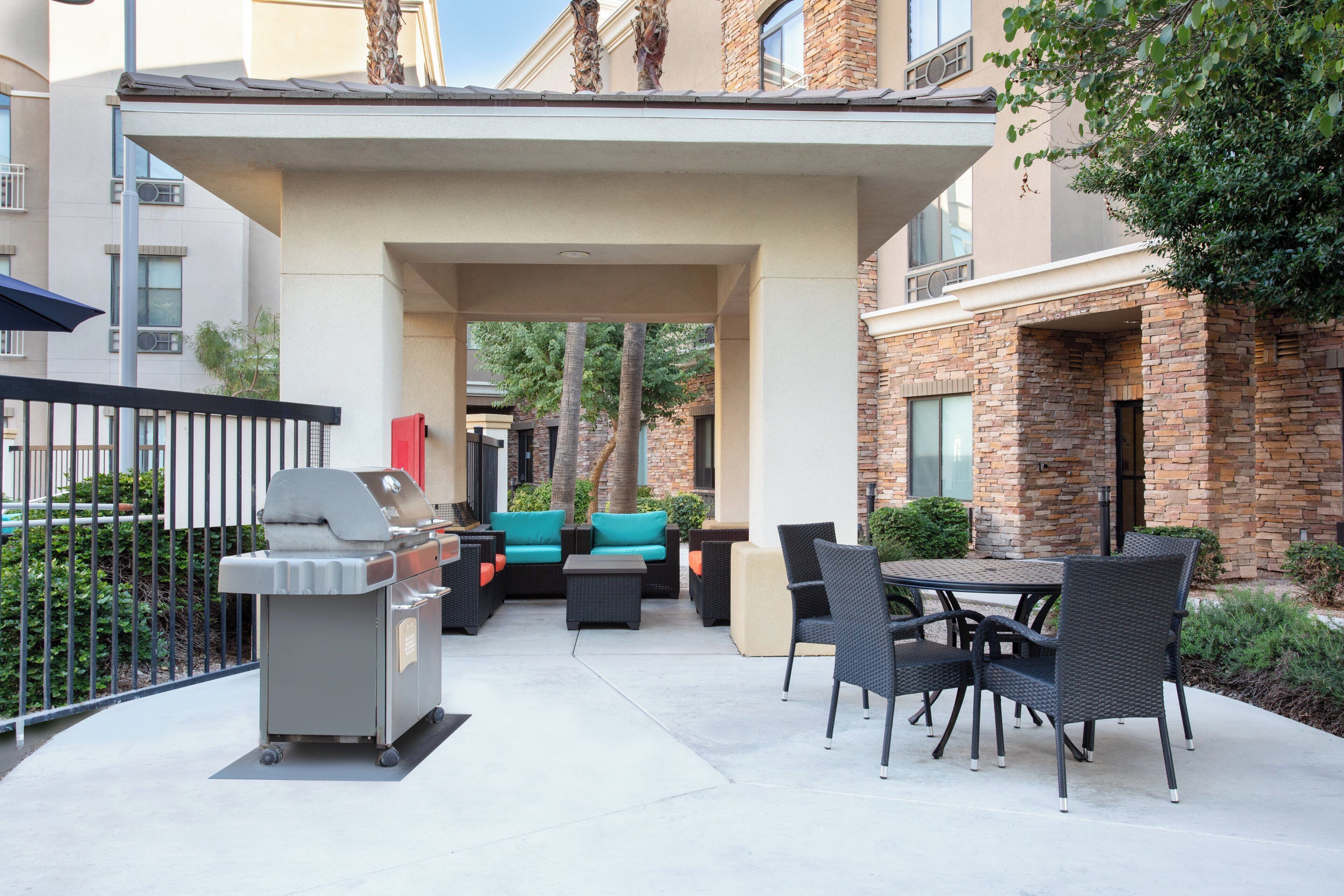 Un espace extérieur aménagé en terrasse, avec un barbecue, des sièges et une vue sur les bâtiments environnants.