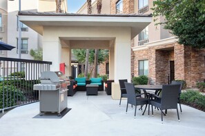 Un'area patio esterna con una griglia, posti a sedere e vista sugli edifici circostanti.