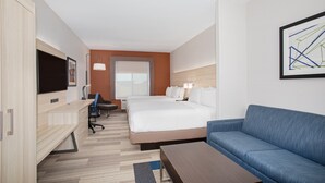 Quarto de hotel com uma cama, um sofá, uma escrivaninha, uma televisão e um quadro na parede.