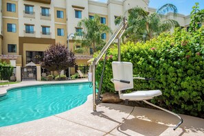Une piscine équipée de chaises longues et d’une rampe d’accès pour fauteuils roulants.