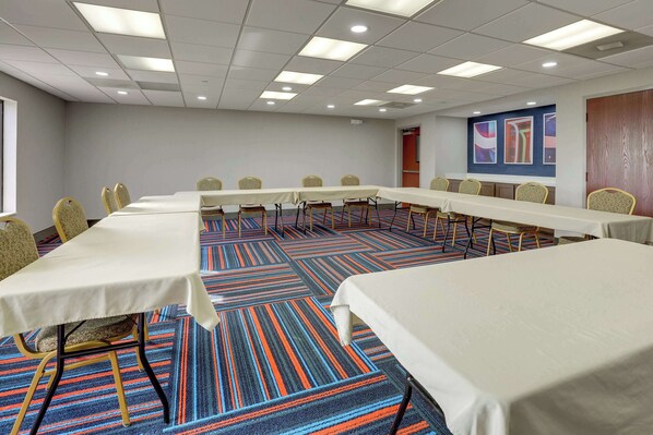 A conference room with a long table, multiple chairs, and a carpeted floor.