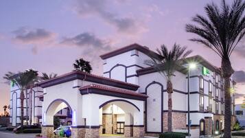 A hotel with a Mediterranean architectural style, featuring arched doorways and a stone facade.