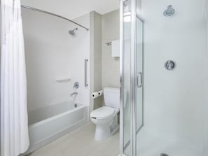 Un baño moderno con ducha de vidrio, inodoro blanco y bañera.
