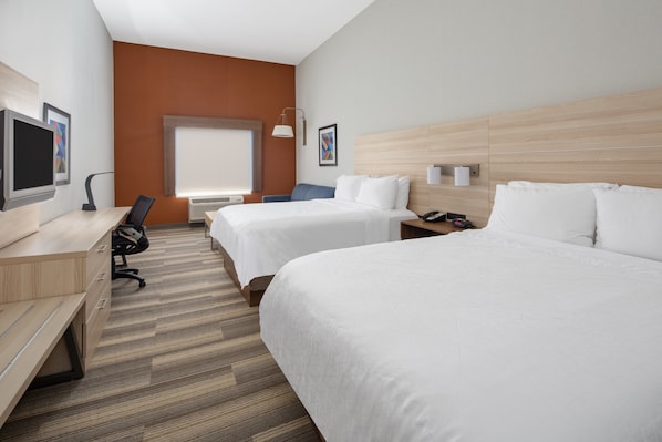 Una habitación de hotel con dos camas, un escritorio, una silla, un televisor y una ventana.