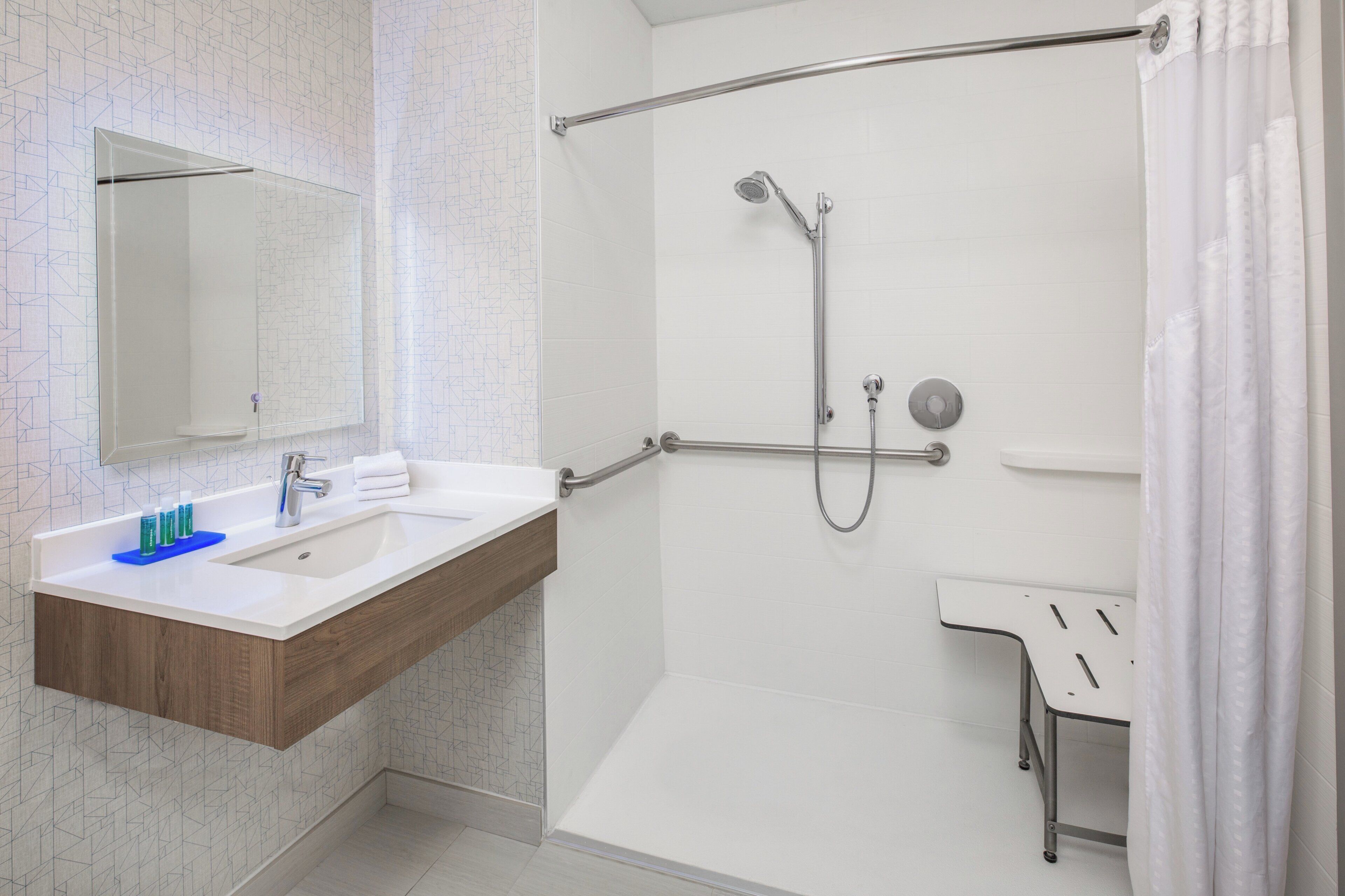 A modern bathroom with a shower, a sink with a mirror, and a small vanity.