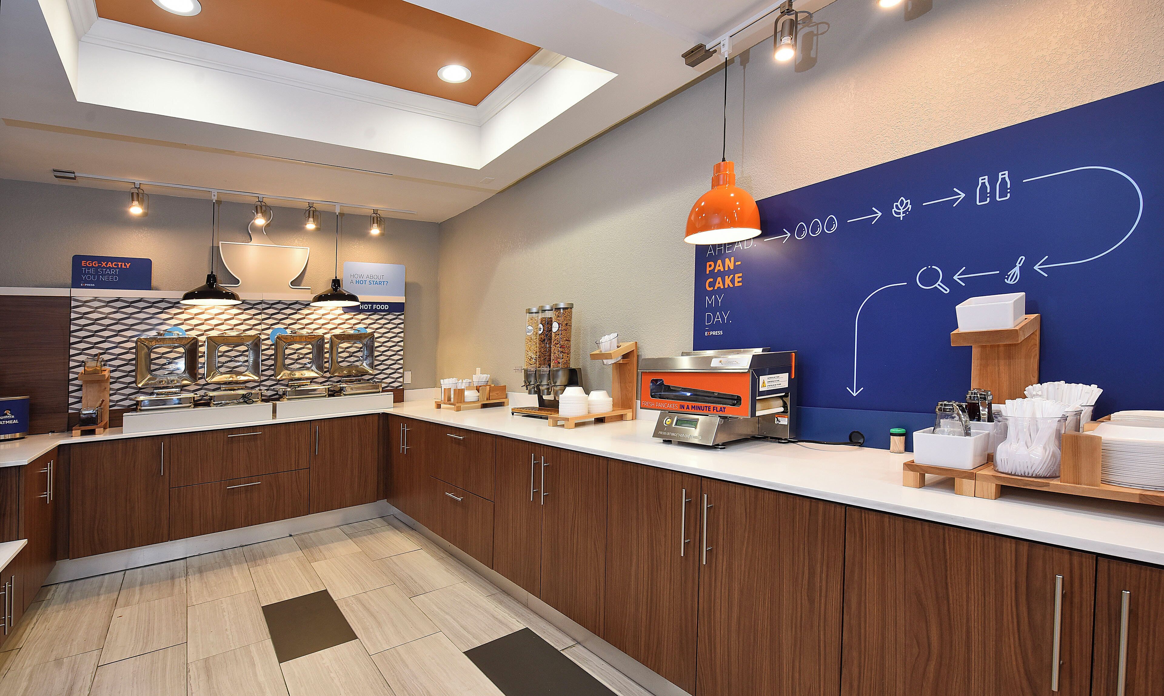 A modern kitchen with a breakfast bar, a coffee machine, and a wall with a food-related diagram.