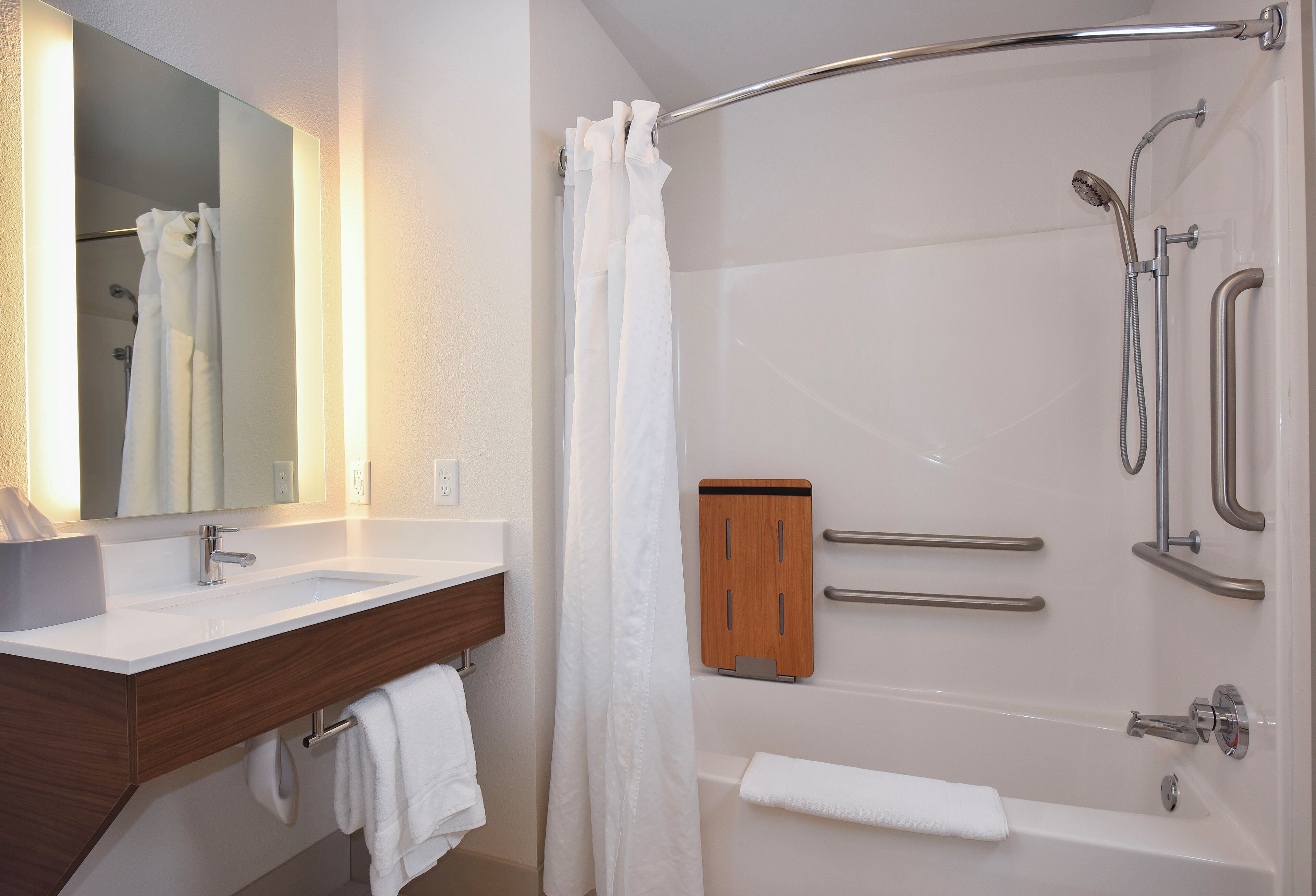 Un baño moderno con lavamanos, espejo y ducha blancos.