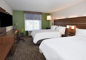 A hotel room with two beds, a desk, a chair, a TV, and a window with a view.