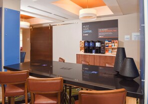 A conference room with a long table, chairs, a coffee station, and a sign advertising coffee. - Holiday Inn Express Selma by IHG (Selma)