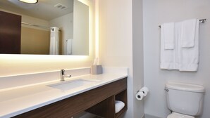 A modern bathroom with a white sink, mirror, and toilet.